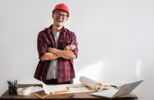 Construction business owner happy with blueprints on the office desk